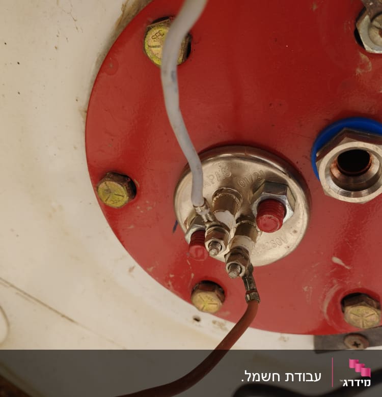 חיבורים חשמליים על לוח מתכת אדום עם ברגים